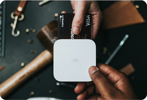Person holding white Apple AirTag tracker device during unboxing with accessories on dark surface