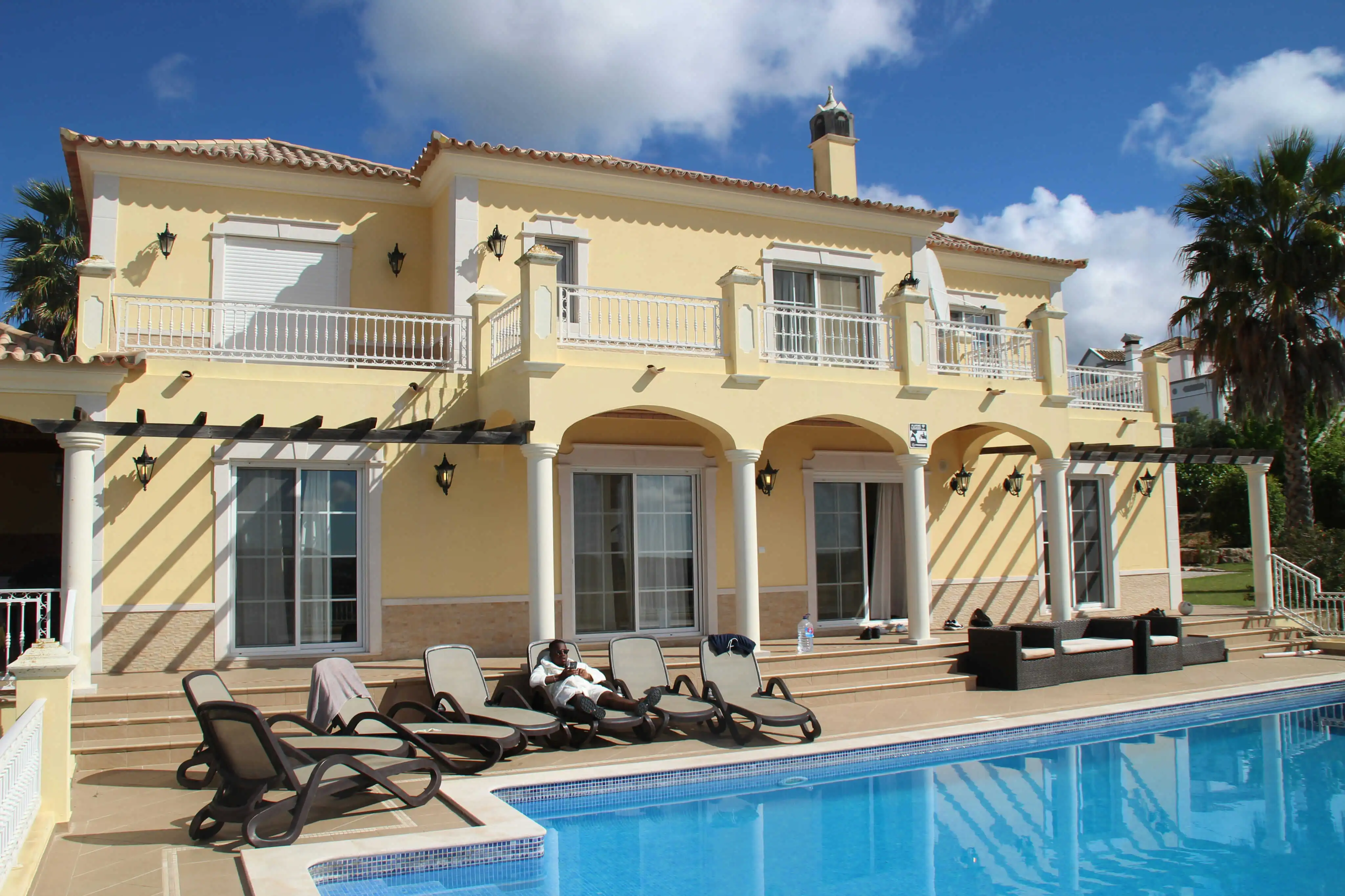 Elegant Mediterranean-style villa with private swimming pool, sun loungers, and arched terrace under a blue sky