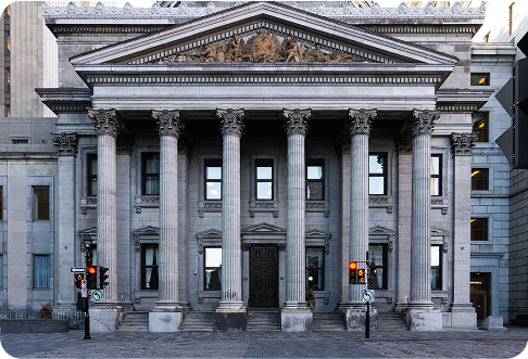 Neoclassical stone building with six tall Corinthian columns, triangular pediment, and ornate architectural details typical of government courthouse or bank
