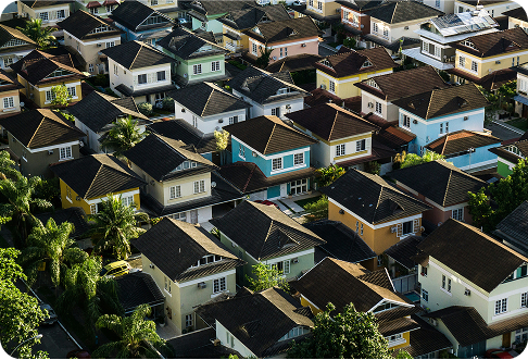 Aerial view of colorful suburban houses with dark rooftops and palm trees