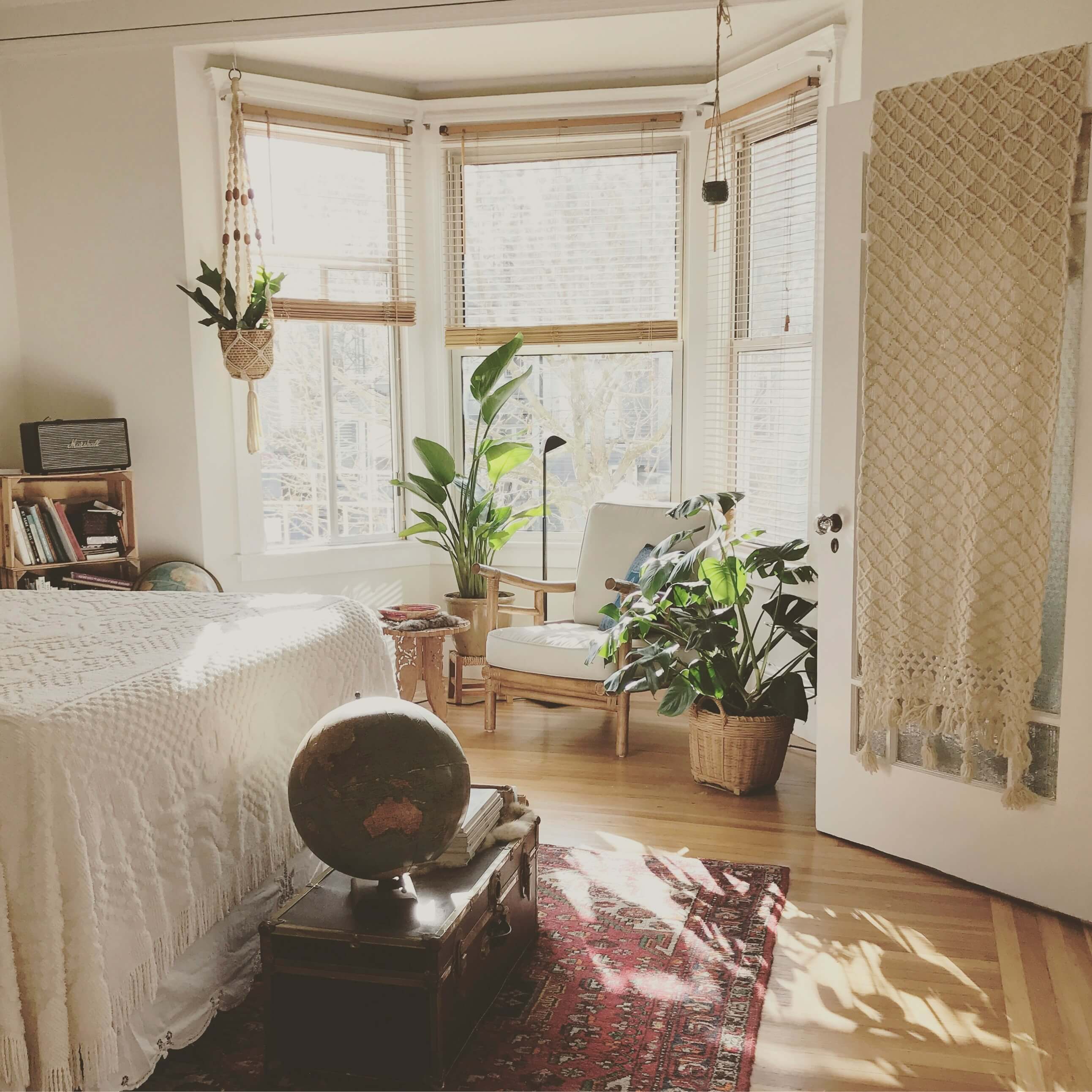 Bright bedroom with plants, bay windows, and cozy natural light